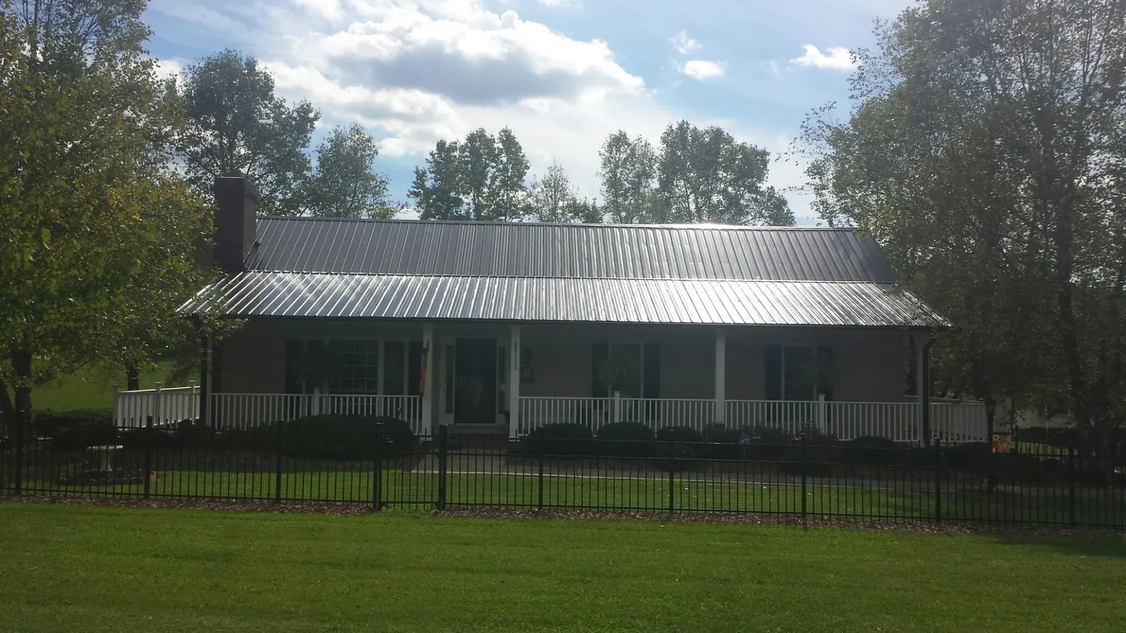Gray metal roof on a brick ranch with a full width front porch — Gutter Guard Installation work by our crew in Princeton